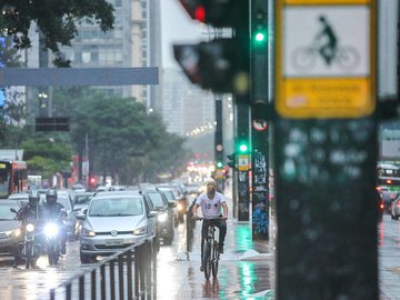 Ciclista pedala na Avenida Paulista em momento de trânsito de carros