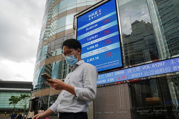 Pessoas passam em frente a tela mostrando cotações de ações na fachada do prédio da bolsa de Hong Kong