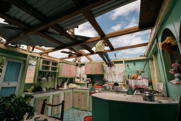Morador da ilha caribenha de Dominica trabalha no conserto de seu telhado após a passagem de um furacão: drama da mudança climática está atingindo também ilhas maiores.